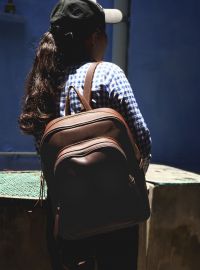 Hoi An Real Leather - Da Bao Real Leather: Aubergine color Vintage style laptop backpack with big front pocket, closing with zipper. Smaller size, girl carrying laptop backpack in Hoi An.